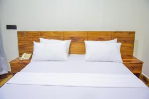 a bedroom with a white bed with a wooden headboard at N-line Residency Hotel in Arusha