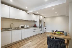 a kitchen with white cabinets and a wooden table at Oceanea Apartment by Homie in Santa Cruz