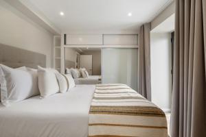 a bedroom with a large white bed with white pillows at Oceanea Apartment by Homie in Santa Cruz