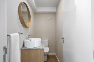 a bathroom with a sink and a toilet and a mirror at Oceanea Apartment by Homie in Santa Cruz +23 photos