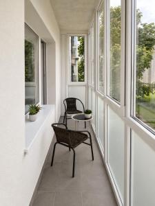 two chairs sitting on a balcony with windows at Town Square Apartment in Panevėžys
