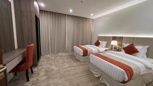 a hotel room with two beds and a desk at Eioraa Hotel فندق إيوراء in Khamis Mushayt
