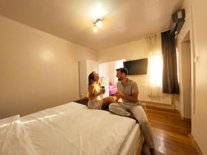 a man and a woman sitting on a bed at Mara by iVAVev in Eforie Sud