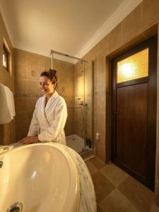 a woman standing next to a bath tub in a bathroom at Mara by iVAVev in Eforie Sud