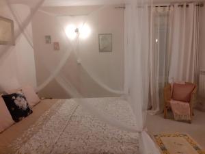 a bedroom with a white bed and a chair at Rêve du Revert in Roz-sur-Couesnon