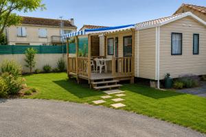 a house with a deck with a table on a lawn at CAMPING PARADIS Domaine Oyat in Le Fenouiller