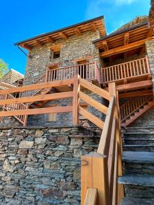 a wooden deck on the side of a stone building at La Mizoun dë Miquél in Ostana