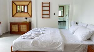 a white bed in a room with a mirror at Ceylon tea resort Ella in Ella +3 photos