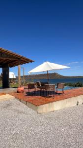 a patio with a table and chairs and an umbrella at Chalé Pontal da Juacema in Ilha Cachoeira