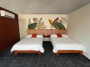 two beds in a room with a mural on the wall at Lol-ha glamp in Temixco