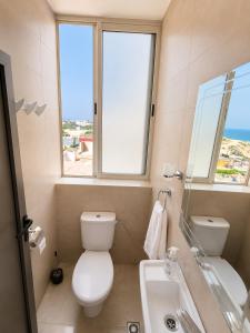 a bathroom with a toilet and a sink and two windows at Miramar Surf Anza in Agadir +88 photos