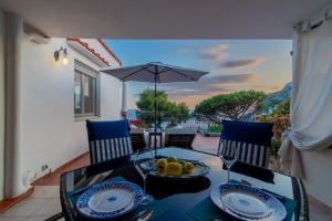 a table with chairs and an umbrella on a balcony at MARVELOUS CAPRI - Sea View Villa in Capri