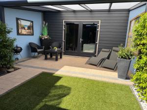 a patio with chairs and a table and a door at Bed & Wellness Chinel Luxe vakantiehuis met Sauna's en Bubbelbad in Sint Annaland +73 photos