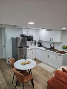a kitchen with white cabinets and a table with chairs at Ope suites Winnipeg in Winnipeg