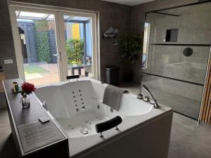 a large bathroom with a tub and a shower at Bed & Wellness Chinel Luxe vakantiehuis met Sauna's en Bubbelbad in Sint Annaland