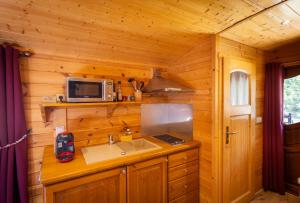 a kitchen with a sink and a microwave in a cabin at Le Pont Rouge Roulotte in Sylvéréal +32 photos