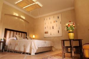 a bedroom with a bed and a vase of flowers on a table at Riad Les Hibiscus in Marrakesh