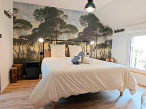 a bedroom with a large bed with a painting on the wall at Le Jardin des 2 Cèdres in Isigny-le-Buat