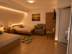 a bedroom with two beds and a chair and a couch at Apartments Maja in Star Dojran