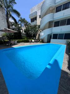a blue swimming pool in front of a building at Tiki’s Penth in Acapulco