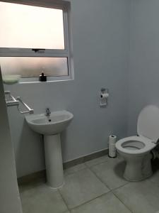 a bathroom with a toilet and a sink and a window at Your Exclusive PMB Escape in Pietermaritzburg +3 photos