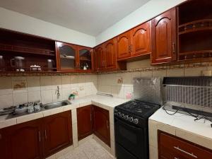 a kitchen with wooden cabinets and a black stove top oven at CIX HOUSE, Casa completa de 3 pisos in Chiclayo