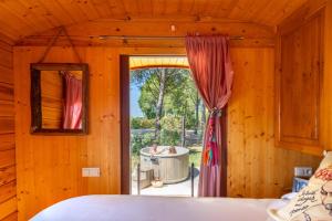 a bedroom with a window with a view of a tub at Le Pont Rouge Roulotte in Sylvéréal