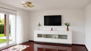 a white living room with a tv on a wall at Cosima in Hohenroth