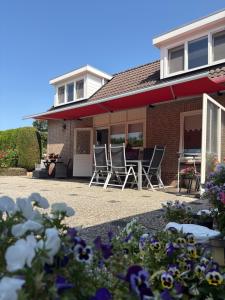 a house with chairs and a table and flowers at Appartementen Koets in Biggekerke