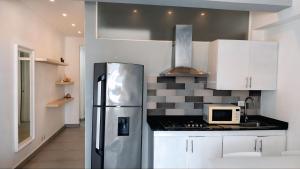 a kitchen with white cabinets and a stainless steel refrigerator at Hotel Bloom Garden Beach Punta Cana in Punta Cana