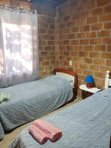 a bedroom with two beds and a brick wall at Casa 2 dormitorios B in Villa Guntz
