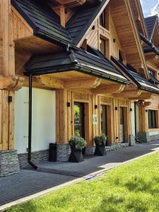 a wooden building with potted plants on a sidewalk at Aparthotel Merynos in Zakopane