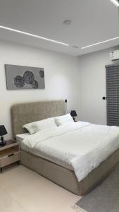 a white bedroom with a large bed and a table at Sweet Sbah in Hail