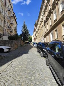 a cobblestone street with cars parked next to buildings at Cozy studio near the Hot Spring in Karlovy Vary