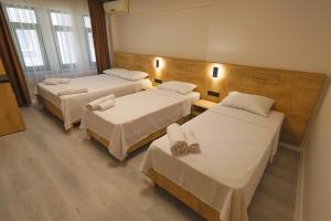a hotel room with three beds and two tables at Doruk Pansiyon in Amasra