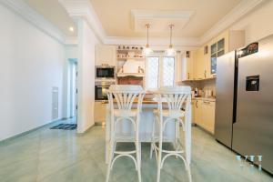 a kitchen with white stools and a black refrigerator at Victory's Luxury House with Jacuzzi on the Roof in Casamicciola Terme