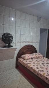 a small bedroom with a bed and a fan at Chacara Maua Eventos in Planaltina