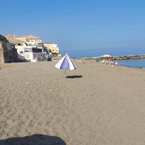 a blue and white umbrella on a sandy beach at Pieds dans l'Eau Douaouda in Fouka