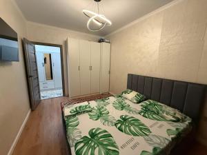 a bedroom with a bed with a green leafy comforter at Жилой Комплекс Kemel-UI in Qaskeleng