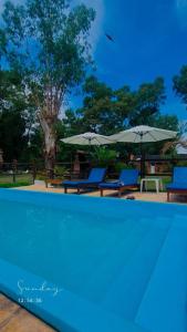 a swimming pool with two chairs and umbrellas at cabañas LA COCA in Lobos
