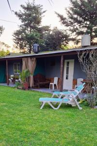 a house with two lounge chairs in the yard at cabañas LA COCA in Lobos