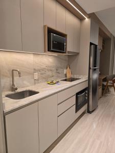 a kitchen with a sink and a refrigerator at Apê Calma - 5min Consulado EUA - Garagem in Porto Alegre