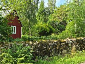 a red house in the woods with a stone wall at Scandinavian forest retreat in Ljungbyhed