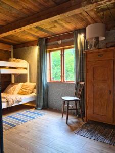 a bedroom with a bunk bed and a chair and a window at Scandinavian forest retreat in Ljungbyhed