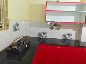 a kitchen with a stove and red cabinets at Aura Vista in Bhopal