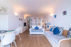 a living room with white furniture and blue pillows at Casa vista Faraglioni Capri in Capri