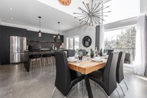 a kitchen with a wooden table and black chairs at Luxurious Villa Tremblant 4 Bdrs W Hot Tub B85 in Mont-Tremblant