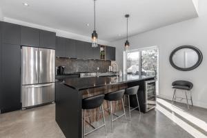 a kitchen with black cabinets and a bar with stools at Luxurious Villa Tremblant 4 Bdrs W Hot Tub B85 in Mont-Tremblant