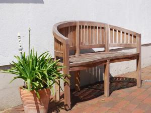 a wooden bench sitting next to a wall with a potted plant at Großes Landhaus mit Swimmingpool in Dargun in Barlin