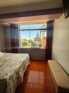 a bedroom with a bed and a large window at APART TOSCANO Suites in Huancayo